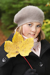 Image showing Cute young woman showing maple leave