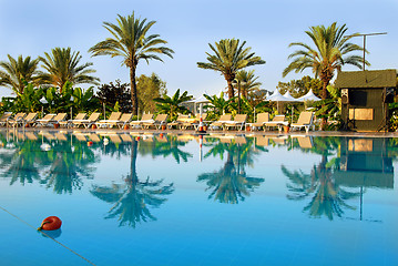 Image showing Palms and chairs by swimming pool