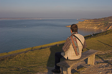 Image showing Man sitting on bench overlooking sea