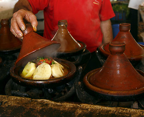 Image showing Market cook holding a cover of a tajine dish (traditional casser