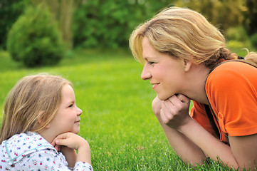 Image showing Young mother and daughter laying on the grass