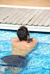 Image showing Young man relaxing at the edge of the swimming pool