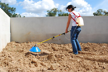 Image showing Young farmer fertilizing the soil