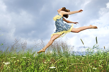 Image showing Young girl jumping in meadow