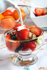 Image showing Cream being poured on Fresh fruit salad in a glass bowl