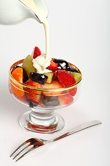 Image showing Pouring cream on to fruit salad