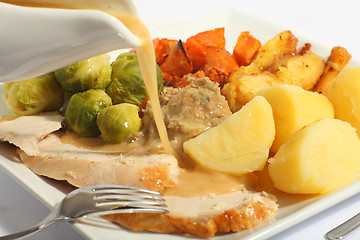 Image showing Pouring gravy on a roast turkey meal