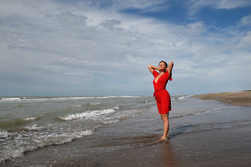 Image showing women in red on oceanic coast under blue sky