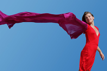 Image showing young women with red fluttering scarf on blue sky background