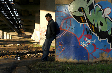 Image showing Young handsome man leaning against the bridge column with colorf