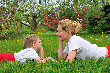 Image showing Young mother and daughter laying on the grass