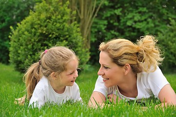 Image showing Young mother and daughter laying on the grass