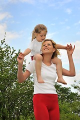 Image showing Young woman carrying her daughter over the shoulders
