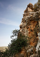 Image showing Steep weathered cliff face over dark sky