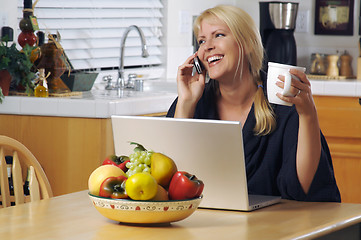 Image showing Woman in Kitchen on Cell Phone & Laptop