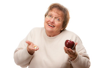 Image showing Confused Senior Woman Holding Apple and Vitamins