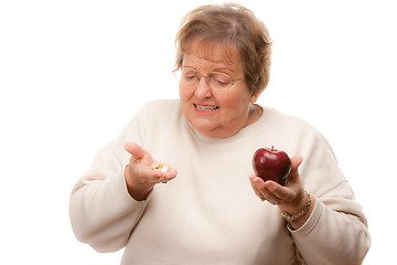 Image showing Confused Senior Woman Holding Apple and Vitamins