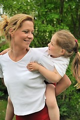 Image showing Young mother giving her child piggyback ride