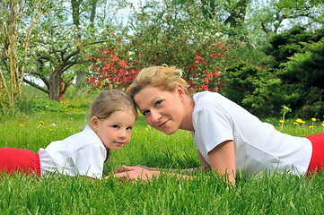 Image showing Young mother and daughter laying on the grass