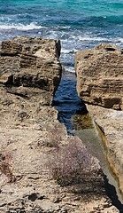 Image showing Narrow crack in the rocks at sea coast in bright summer day