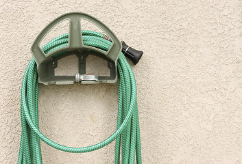 Image showing Garden Hose Hanging on Stucco Wall