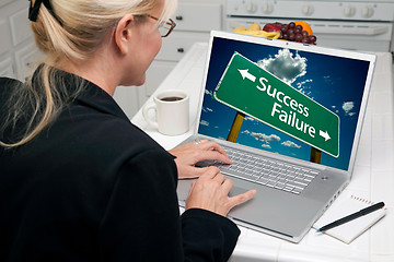 Image showing Woman In Kitchen Using Laptop with Success and Failure Road Sign