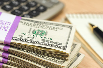 Image showing Stack of Money, Calculator, Paper and Pen