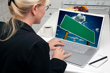 Image showing Woman In Kitchen Using Laptop with Blank Road Sign on Screen