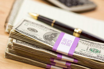 Image showing Stack of Money, Calculator, Paper and Pen