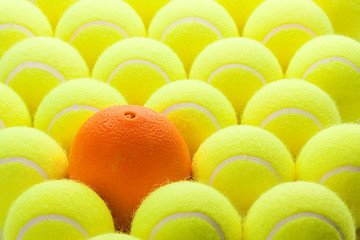 Image showing Group of Tennis Balls and One Orange