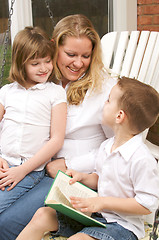 Image showing Young Boy Reads to His Mother and Sister