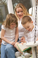 Image showing Young Boy Reads to His Mother and Sister