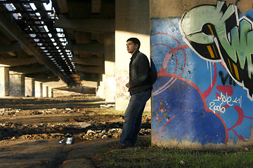 Image showing Young handsome man leaning against the bridge column with colorf