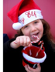 Image showing Little girl in Elf Hat eating candy canes