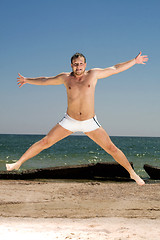 Image showing Bizarre young man jumping on a beach
