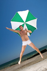 Image showing Bizarre young man with umbrella on a beach
