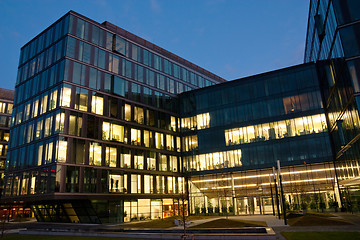 Image showing complex of office buildings from glass in the evening with the windows