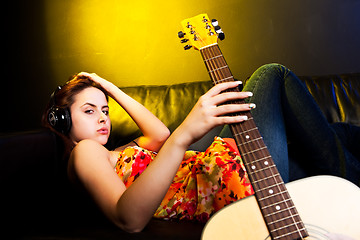Image showing Beautiful woman with headphones and guitar