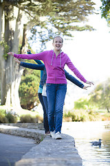 Image showing 3 Tween Girl Balancing On Wall By Pond