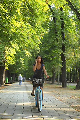 Image showing Woman on the phone riding bicycle