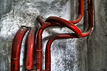 Image showing Red bent pipes on concrete walls