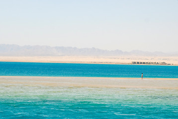 Image showing Lonely man walking on sand beach