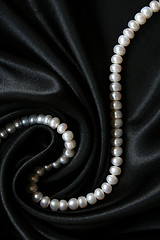 Image showing White pearls on the black silk as background 