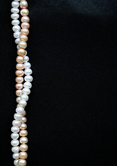 Image showing White and pink pearls on the black silk background