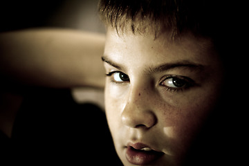 Image showing Young boy looking up with hope in his eyes low key sephia tonned