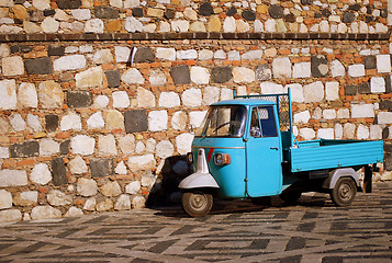 Image showing Blue tricycle scooter in front of stone wall