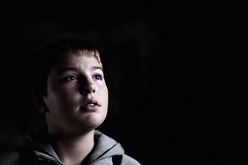 Image showing Young boy looking up with hope in his eyes Low key high contrast copy space