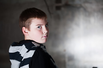 Image showing Boy looking over the shoulder against grunge background lit with flash