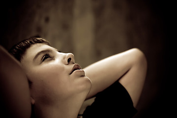 Image showing Young boy looking up with hope in his eyes sepia toned low key