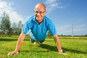 Image showing Middle-aged man doing push-ups